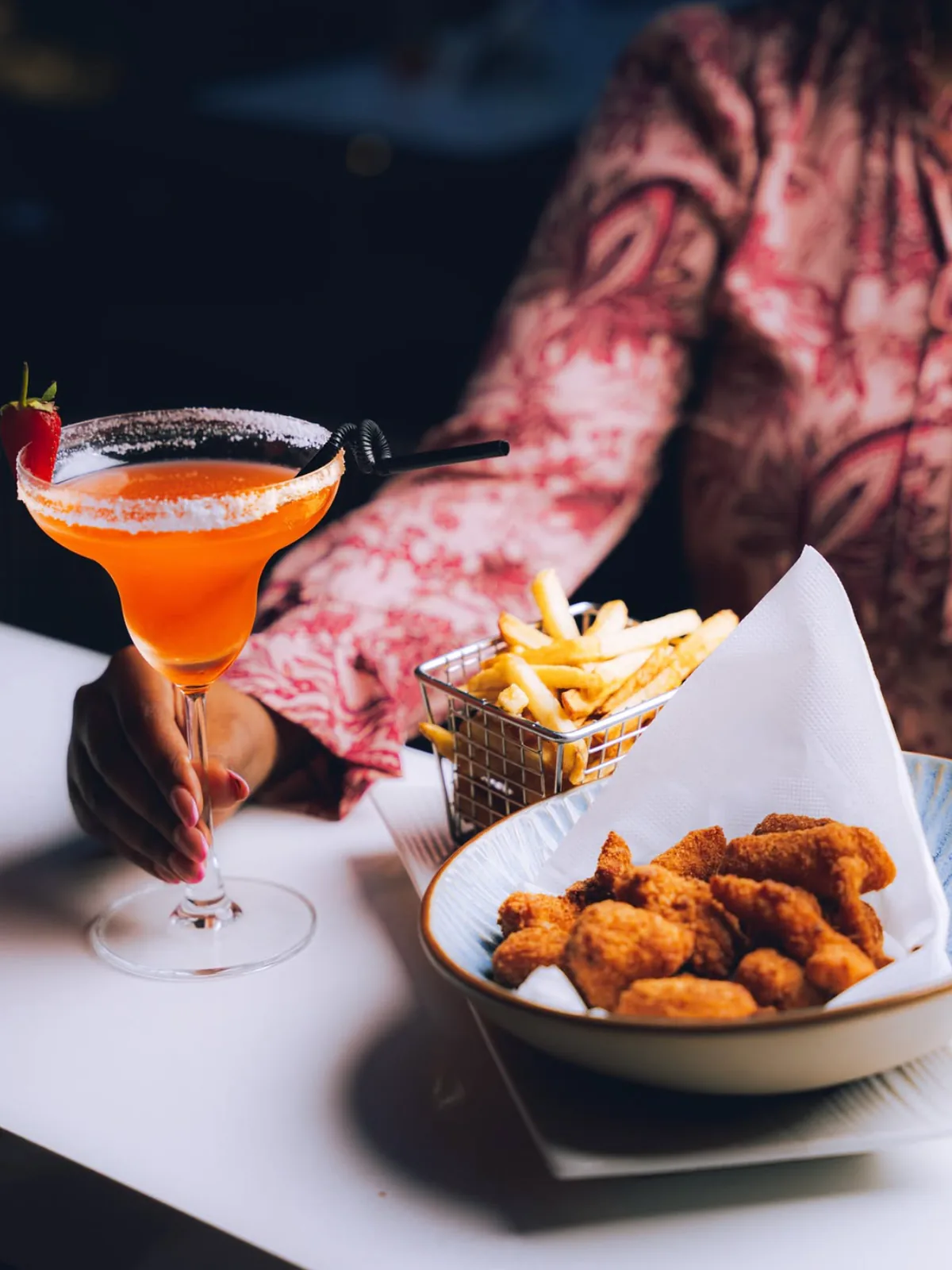 Savor fried bites, fries, and a bright orange drink shared at the table